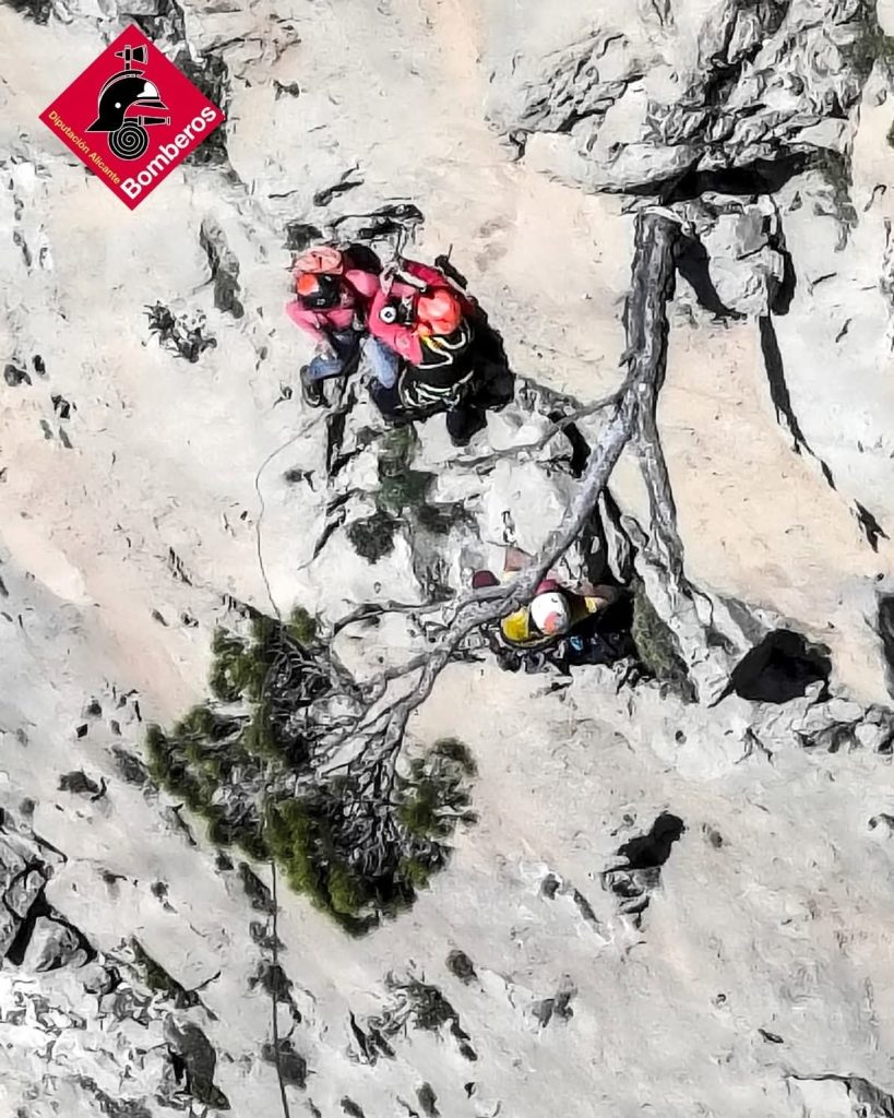 Rescate en el Puig Campana: una escaladora resulta herida tras caer en la vía Julia y es evacuada en helicóptero Los bomberos del Consorcio Provincial de Alicante realizan un complejo rescate aéreo en la pared del Puig Campana, en Finestrat Una escaladora ha resultado herida este viernes tras sufrir una caída mientras ascendía la conocida vía Julia del Puig Campana, en el término municipal de Finestrat (Alicante). El rescate ha requerido la intervención del helicóptero de emergencias y del grupo especializado de rescate del Consorcio Provincial de Bomberos. El aviso se ha recibido a las 13:37 horas, activándose inmediatamente el operativo de rescate. La intervención ha finalizado a las 14:58 horas, tras evacuar a la víctima en helicóptero. La caída se produjo en el tercer largo de la vía Según han informado fuentes del operativo, una cordada formada por tres escaladores se encontraba ascendiendo la vía Julia del Puig Campana cuando, a la altura del tercer largo, la escaladora sufrió una caída. Tras el accidente, la mujer se golpeó en los pies y resultó lesionada en ambos tobillos, lo que le impidió continuar la actividad. Sus compañeros lograron descenderla hasta la segunda reunión de la vía, donde permanecieron asegurados a la espera de la llegada de los equipos de rescate. Un rescate aéreo complejo por la presencia de árboles y otros escaladores Hasta el lugar se desplazó el helicóptero Alpha 01 del Consorcio Provincial de Bomberos de Alicante con el Grupo Especial de Rescate (GER). El operativo no fue sencillo. Los rescatadores tuvieron que realizar una maniobra de grúa de gran longitud, además de sortear varios árboles presentes en la zona de pared. A esta dificultad se sumó la presencia de otros escaladores en la vía, lo que obligó a extremar las precauciones durante la operación aérea. Finalmente, los especialistas lograron izar a la escaladora hasta el helicóptero de rescate. Traslado a la helisuperficie de Finestrat Una vez completada la evacuación, la víctima fue trasladada en el helicóptero Alpha 01 hasta la helisuperficie de Finestrat, donde fue transferida a un recurso sanitario para su valoración y asistencia médica. En el operativo participaron: Helicóptero de rescate Alpha 01 GER (Grupo Especial de Rescate) del Consorcio Provincial de Bomberos de Alicante Las autoridades recuerdan la importancia de extremar las medidas de seguridad en actividades de montaña y escalada, especialmente en zonas de gran afluencia como el Puig Campana.