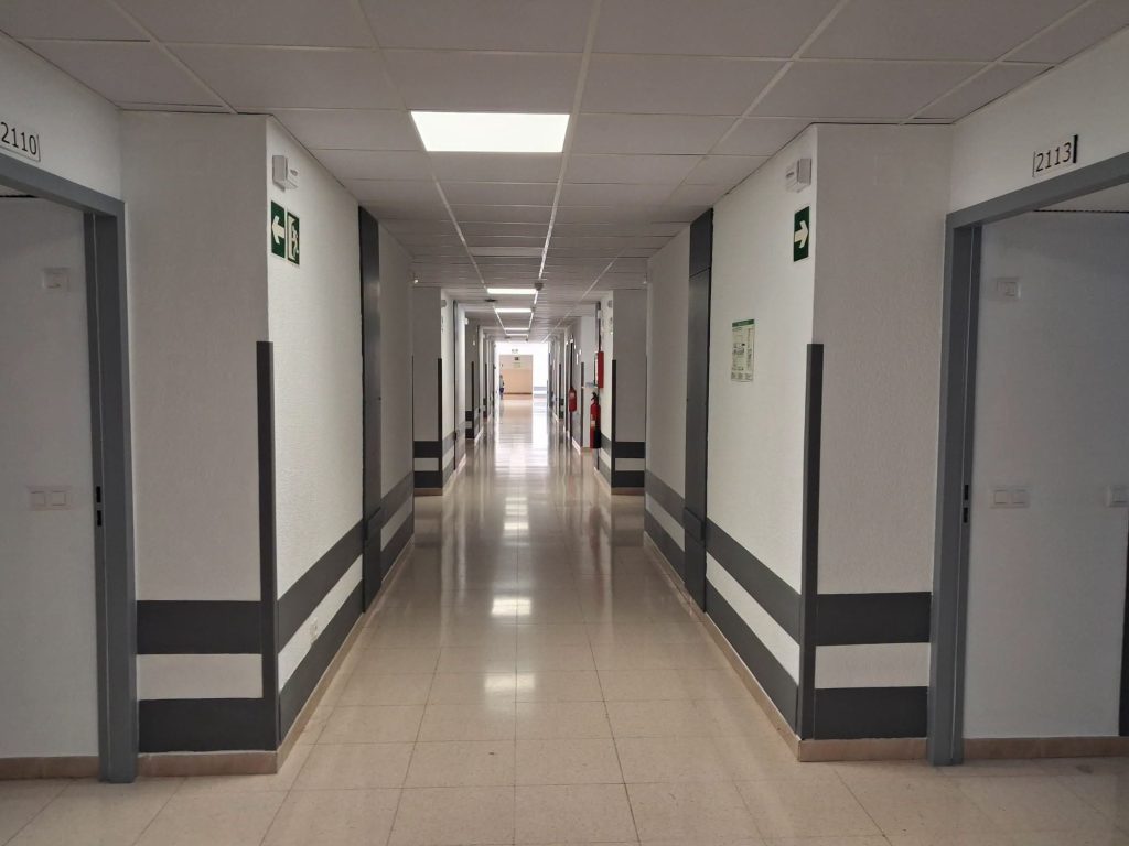 El Hospital Marina Baixa reabre la planta de Traumatología tras una inversión de 39.000 euros El Hospital Universitario Marina Baixa ha culminado este miércoles la reapertura total de su planta de hospitalización de Traumatología. La entrada en servicio de las instalaciones se produce tras dos meses de obras de acondicionamiento y una inversión pública de 38.913,60 euros destinada a modernizar los espacios comunitarios y las habitaciones del área. La recuperación del servicio se ha ejecutado de manera escalonada para minimizar el impacto en la actividad asistencial. Tras una primera fase activada el pasado 5 de septiembre con la puesta en marcha de 10 unidades, el centro sanitario vuelve a disponer de la totalidad de sus 34 camas operativas. Mejoras en el confort y el control asistencial Los trabajos de remodelación han abarcado tanto las zonas de trabajo de los profesionales como los espacios de ingreso de los pacientes: Zonas comunes y de enfermería: Se ha renovado íntegramente el mostrador del control de Enfermería, se ha instalado un nuevo sistema de iluminación y se han cambiado los techos de escayola. Mantenimiento general: Pintado completo de paredes y puertas en toda la planta. Habitaciones y equipamiento: Instalación de nuevos sillones para los ingresados, sustitución de rieles y cortinas separadoras de espacio y renovación de la fontanería higiénica, incluyendo un nuevo fregadero para cuñas y la actualización de los aseos. Con la finalización de estos trabajos, el centro sanitario ubicado en La Vila Joiosa optimiza la calidad de la atención hospitalaria y recupera su capacidad operativa del área quirúrgica y traumatológica.